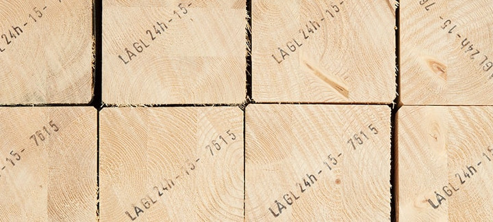 Gestapelte Brettschichtholzbalken mit sichtbarer Jahresringstruktur und Markierungen für den Holzbau.